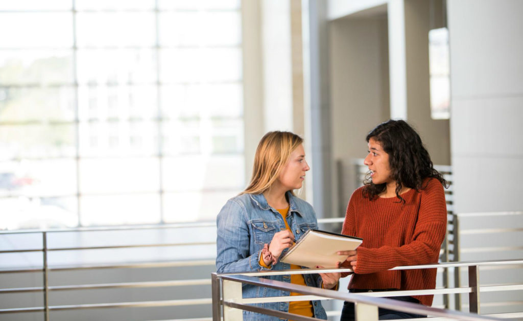 students talking in hallway of campus building