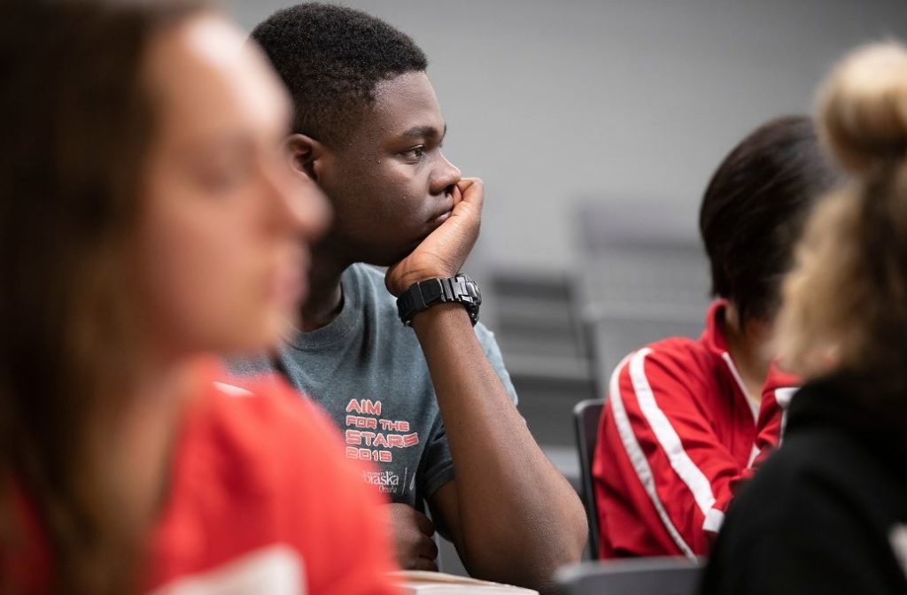 student in classroom with hand under chin