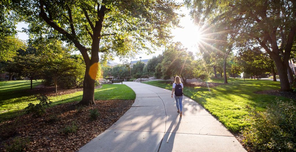 student walking through campus on a sunny day